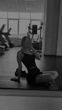 a woman taking a selfie in front of a gym machine with her cell phone