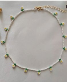 a white beaded necklace with yellow and green flowers