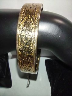 A beautiful vintage 19th-century Victorian taille d'epargne bangle bracelet made by Bliss Bros. The etched floral bangle bracelet is stamped B Co in a large B.  It's 1/20 12K and measures 57mm around the inside and 13 mm wide. The yellow gold-filled bangle has its original Safety chain and a Strong push-in clasp, In beautiful antique condition, the bracelet shows minor wear. Antique Hallmarked Yellow Gold Bangle, Antique Yellow Gold Hallmarked Bangle, Vintage Yellow Gold Bangle Gift, Vintage Yellow Gold Bangle For Gift, Victorian Etched Cuff Bracelet, Victorian Engraved Gold Bracelet, Victorian Etched Cuff Bracelet For Wedding, Antique Cuff Bracelet With Intricate Design For Formal Occasions, Antique Round Cuff Bracelet For Wedding