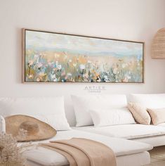 a white couch sitting under a painting on the wall