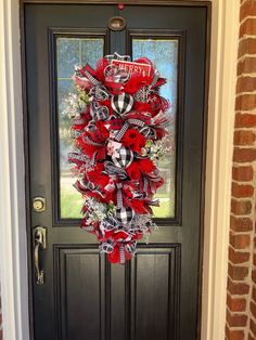 a red and black christmas wreath hanging on the front door