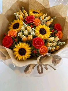 a bouquet of sunflowers and roses wrapped in brown paper