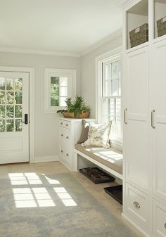 the sun shines through the windows in this white room with built - in storage