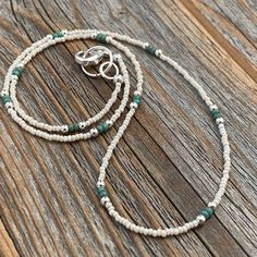 two white and green beaded bracelets on wooden surface