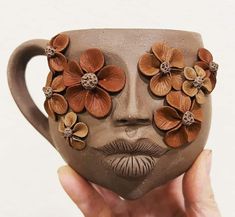 a person holding up a coffee mug with flowers on it's face and nose