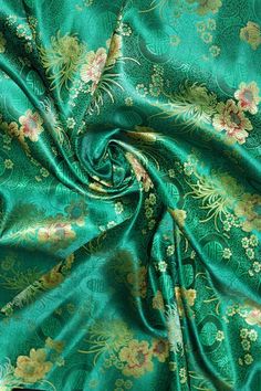 a green fabric with gold and pink flowers on the bottom, it is very soft