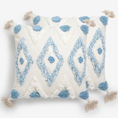 two blue and white pillows with tassels on them