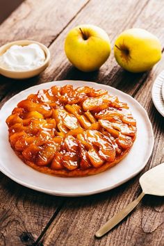 an apple tart on a white plate next to some apples