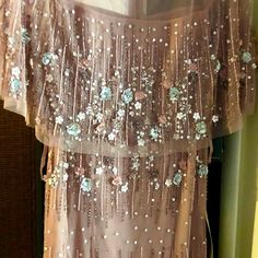 an image of a dress hanging up in the closet with beads and flowers on it