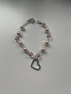 this pearl charm bracelet comes with a sterling silver heart charm, white and pink pearls, pink glass beads, and an adjustable clasp. this is a perfect gift for a loved one or for Valentine's Day! Pink Pearl Bracelet With Pearl Charm, Adjustable Pink Pearl Bracelet With Pearl Drop, Pearl Beaded Bracelets With Heart Beads, Heart-shaped Beaded Pearl Bracelet Gift, Silver Heart-shaped Pearl Bracelet For Gift, Pearl Bracelets With Heart Beads, Adjustable Pearl Bracelets With Heart Charm, Adjustable Pearl Heart Bracelet, Pink Pearl Bracelet With Pearl Drop