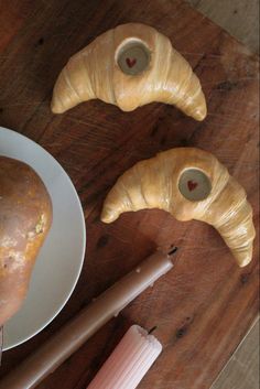 two croissants on a white plate next to a knife and some other items