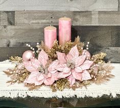 two pink candles sitting on top of a table next to some flowers and other decorations