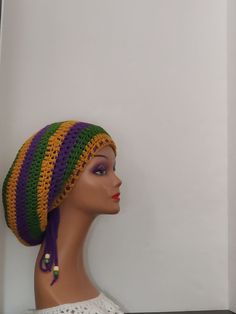 This handmade crochet dreadlock tam beanie hat is perfect for those who love the colorful and vibrant spirit of Mardi Gras, as well as the laid-back vibe of reggae, rastafarian, and boho cultures. The hat features a striped pattern in purple, green, and gold, with wooden bead accents that add a touch of earthy charm. The drawstring, stretch, and adjustable features of the hat make it comfortable to wear for all head sizes, while the breathable acrylic material keeps you cool in summer and warm in winter. Handmade Multicolor One Size Headwrap, Handmade Multicolor One-size Headwrap, Bohemian Beanie Headwrap, Purple Bohemian Yarn Hat, Bohemian Purple Adjustable Crochet Hat, Bohemian Adjustable Purple Crochet Hat, Bohemian Slouchy Crochet Hat For Beach, Adjustable Bohemian Purple Crochet Hat, Bohemian Purple Crochet Hat