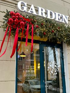 a store front with christmas decorations on the window and red ribbon hanging from it's windows