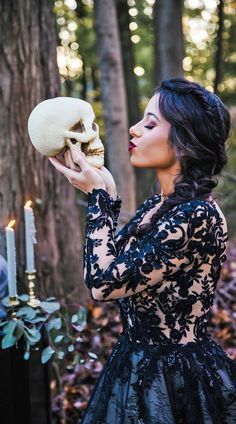 a woman holding a human skull in front of her face while wearing a black lace dress