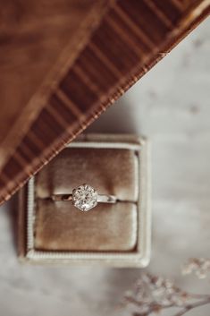 an engagement ring sits in a velvet box