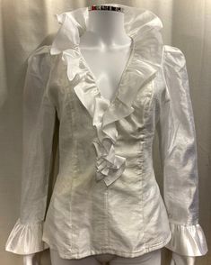 "This is an authentic 1980s ruffle blouse in white Organza. Details in include a deep V neck with large frilled collar, frilled cuffs and a fitted waist. It is fully lined and has a long zip at the back for opening. Size and fit: This top is fitted and there is no stretch to the fabric. The waist measures 28\" and the chest is approximately 36\". It would best fit a UK size 8-10. Condition: This top is in good vintage condition however, there is a pale yellowish stain around the waist area, as shown in the last photo." 80s Ruffle Blouse, Victorian Ruffle Blouse, Frill Collar Blouse, Formal V-neck Blouse With Ruffles, Elegant V-neck Ruffled Blouse, Elegant Ruffled V-neck Blouse, Elegant White Tops With Ruffle Hem, Elegant White Top With Ruffle Hem, Elegant V-neck Ruffle Blouse