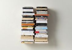 a stack of books sitting next to each other on top of a white wall mounted shelf