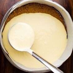 a spoon is sitting in a bowl filled with cheesecake batter and ready to be eaten