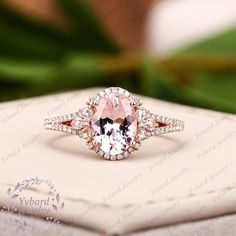 an engagement ring with a pink diamond in the center on top of a white box