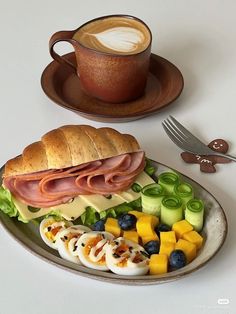 a plate with some food on it next to a cup of coffee and a fork