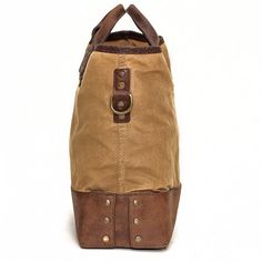 a brown and tan bag with two straps on the front is sitting against a white background