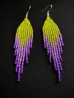 purple and yellow seed beaded earrings with silver hooks on a black background, closeup