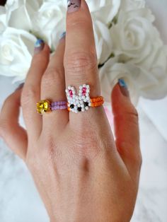 a woman's hand with two rings on it and flowers in the back ground