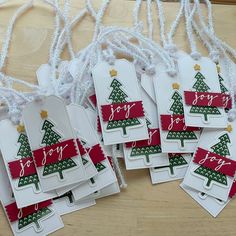 four tags with christmas trees on them are sitting on a table next to some string