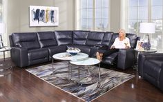 a woman sitting on a couch in a living room next to a table and chairs