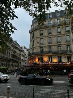 cars are parked on the street in front of a building with an open balcony and balconies