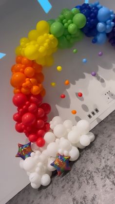 there are many balloons in the shape of a rainbow and stars on the wall next to it