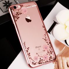 an iphone case with flowers on it sitting on a table next to a flower vase