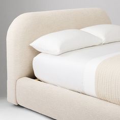 a bed with white sheets and pillows on top of it's headrests