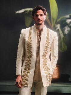 Step into refined elegance with the Kaju Katli Raja koti, an opulent sherwani adorned with intricate gold zardozi, katdana, and pearl embroidery, inspired by 'Berry Bel'. The ensemble includes a short georgette tissue kurta that adds a playful touch and straight, tailored pants for a smart finish. This piece is a perfect blend of grandeur and modern sophistication. Chanderi Bandhgala With Traditional Drape For Designer Wear, Beige Gota Work Anarkali Set For Wedding, Beige Anarkali Set With Gota Work For Wedding, Elegant Chanderi Bandhgala For Transitional Season, Dola Silk Cutdana Kurta For Reception, Reception Dola Silk Kurta With Cutdana, Festival Chanderi Bandhgala For Reception, Reception Cutdana Dola Silk Kurta, Transitional Cutdana Bandhgala For Reception