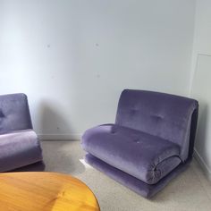 two purple chairs sitting next to each other in a room