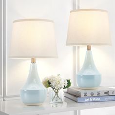 two blue vases sitting on top of a table next to a book and lamp