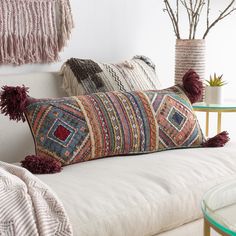 a white couch with two pillows on top of it next to a glass table and potted plant