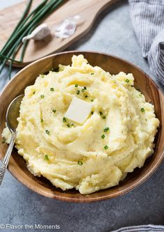 mashed potatoes with butter and parsley in a wooden bowl on a gray table