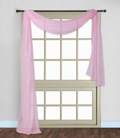 an open window with pink sheer curtains in front of it and wood flooring on the side