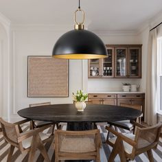 a dining room table with chairs and a large black light hanging from it's ceiling