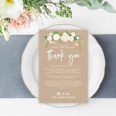 a wedding thank card on top of a plate with flowers and greenery in the background