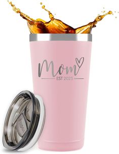 a pink tumbler with the words mom on it and a splash of orange juice