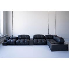 a black leather couch sitting on top of a white floor next to a metal pole