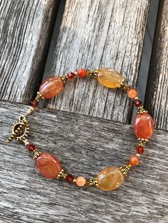 Red Agate is a gem that resembles the colors of the warmest sunsets... alluring and vivid, this bracelet is designed to entice thoughts of the setting sun.  The oval beads showcase the natural color striations and unique patterns found in Agate.  Swarovski crystals in tonal hues compliment the unique, glowing shades of red, orange and yellow these gems display.  Goldfilled beads and gold plated pewter accents continue the warm feeling of this bracelet which closes with a beaded toggle clasp.  As the bracelet moves on your wrist, it will catch your eye as each gem radiates a sense of passion for life! For those interested in the metaphysical properties of gems, Red Agate is thought to "strengthen your inner balance" and "keep negative energy away from the wearer"... Red Agate : Beaded Toggle Clasp, Red Beaded Bracelet, Inner Balance, Passion For Life, Oval Beads, Setting Sun, Agate Bracelet, Red Agate, Orange And Yellow