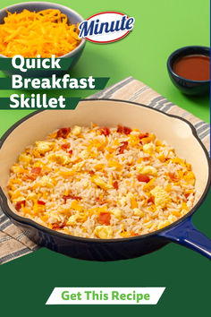 a skillet filled with rice and cheese on top of a green tablecloth next to two bowls of sauce