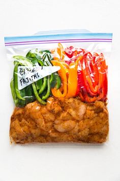 a bag filled with chicken and peppers on top of a white table next to a knife