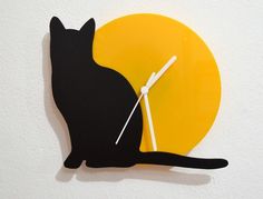 a clock with a black cat sitting on it's side in front of the sun