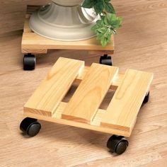 a wooden toy car sitting on top of a hard wood floor next to a potted plant