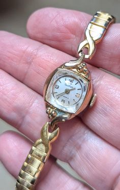 This is a beautiful Waltham gold tone watch that is currently working! I am not a watch expert, nor have I had it tested or serviced, it is being sold AS IS. I can't guarantee for how long it will continue to work. I've wound it several times and it keeps fairly good time, not perfect, but ok. I would strongly recommend having it serviced by a professional. The face is a circle within a square outer case, I love these! It has an ivory face, gold hands and gold numerals. The band is stretch makin Gold Metal Watches For Wedding, Antique Gold Watches For Wedding, Heirloom Gold Jewelry And Watches For Wedding, Vintage Gold Jewelry And Watches For Anniversary, Victorian Gold Watch For Weddings, Antique Gold Wedding Watches, Antique Metal Watches For Formal Occasions, Gold Victorian Watches For Weddings, Vintage Metal Watch For Formal Occasions